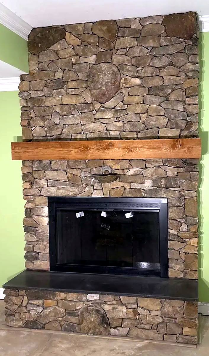 Natural stone fireplace with wood mantel